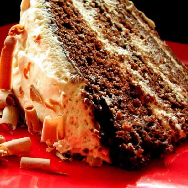 Slice of chocolate cake with whipped cream frosting on a red plate.