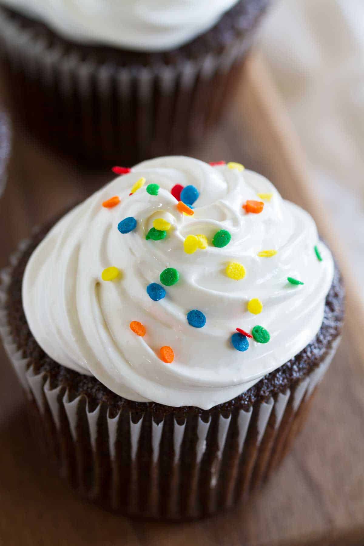 Devil's Food Cupcake topped with white fluffy frosting and rainbow sprinkles.