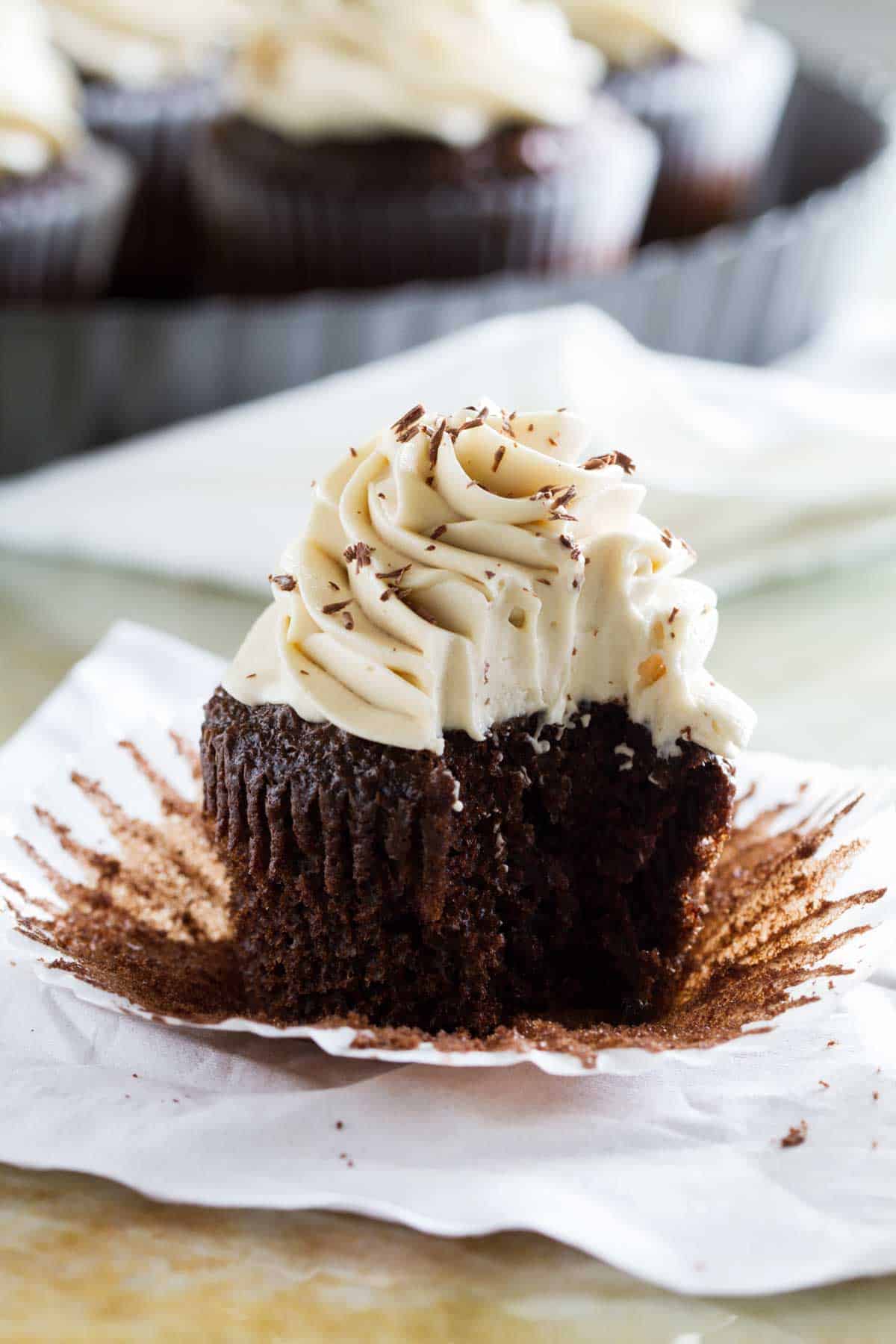 Whipped Cream Cream Cheese Frosting on a chocolate cupcake with a bite taken from it.