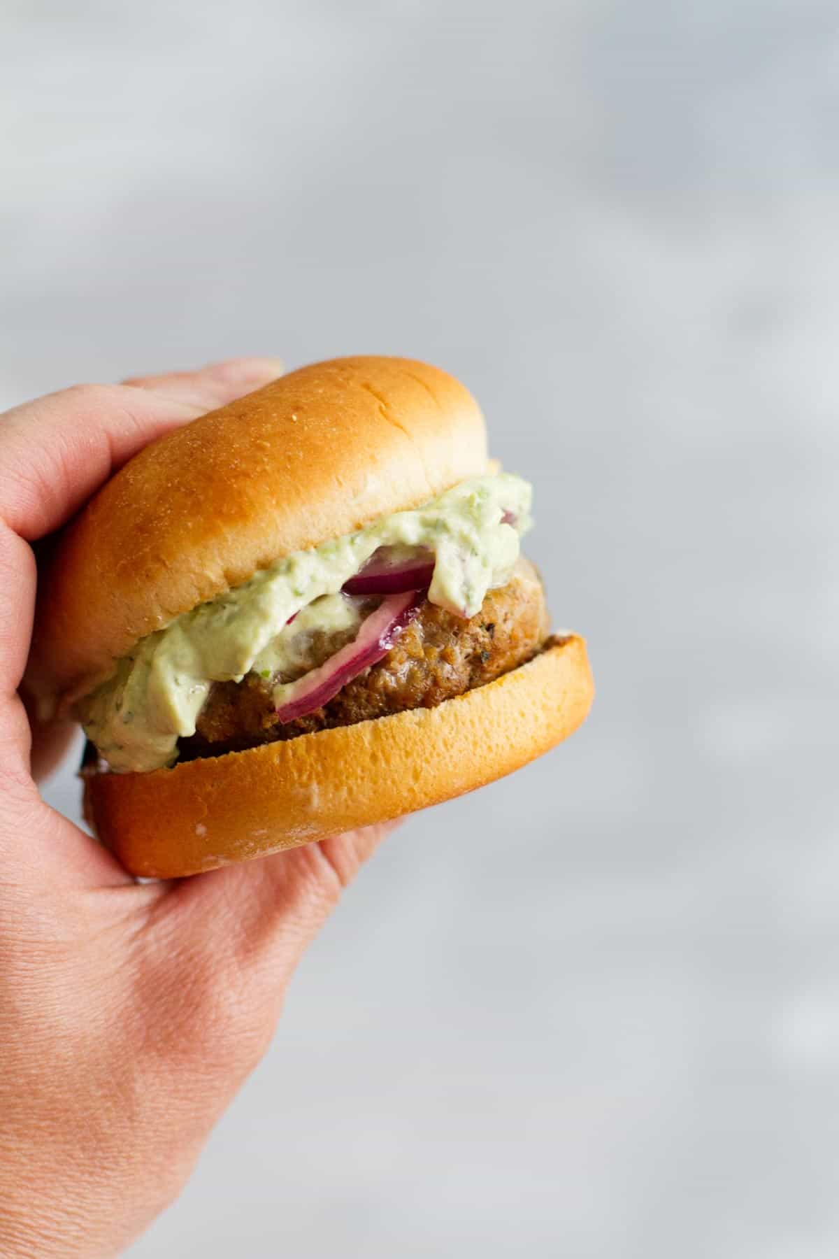 Hand holding a poblano pepper slider burger.