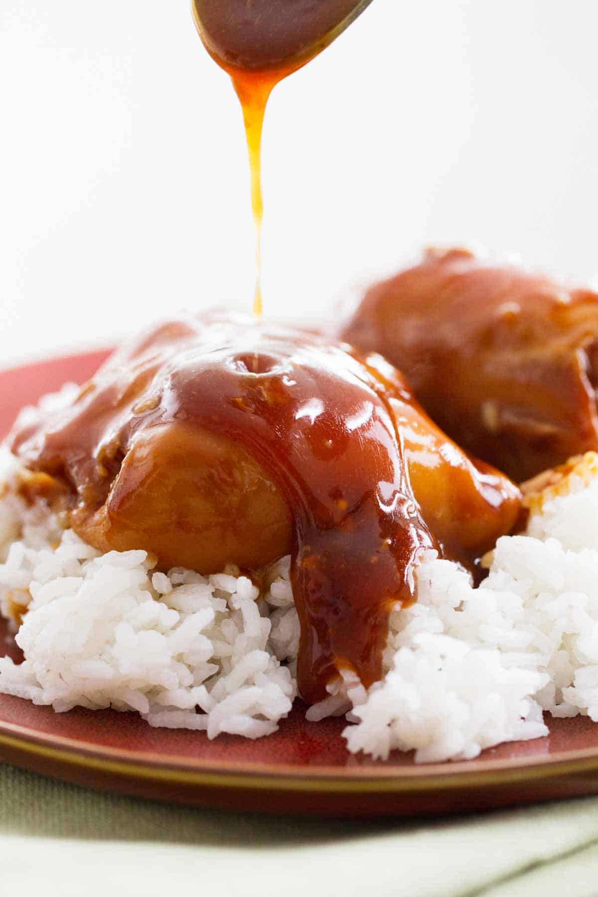 Drizzling sauce over slow cooker honey garlic chicken.