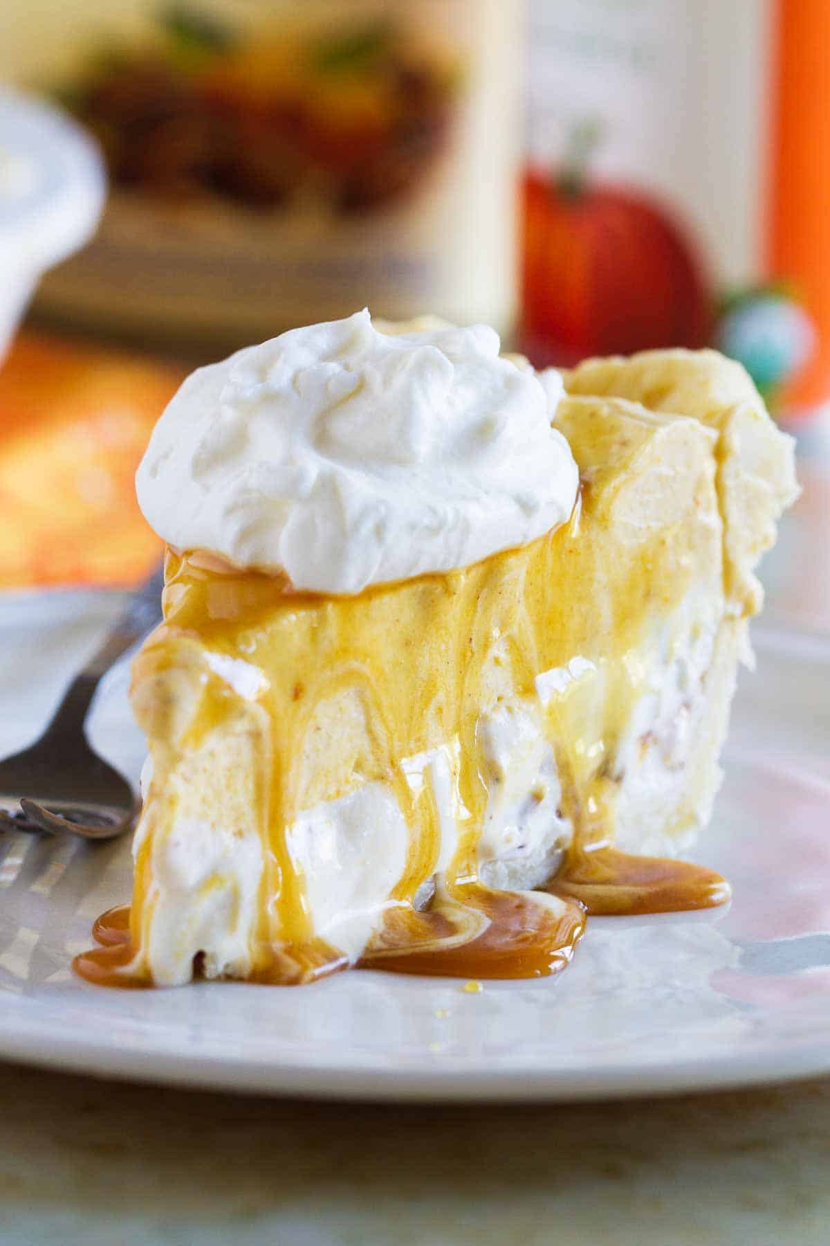 Slice of pumpkin and butter pecan ice cream pie on a plate with whipped cream.