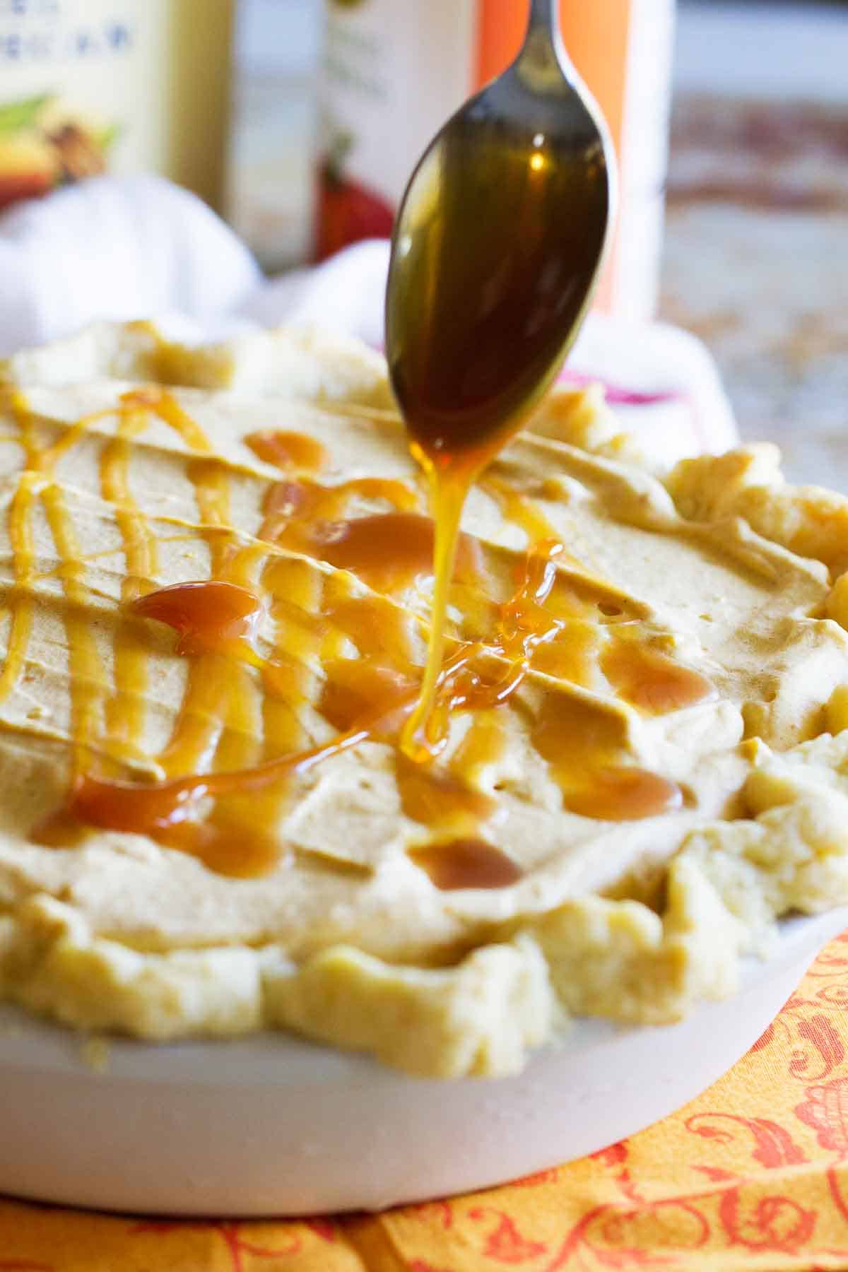 Drizzling caramel over the top of pumpkin and butter pecan ice cream pie.