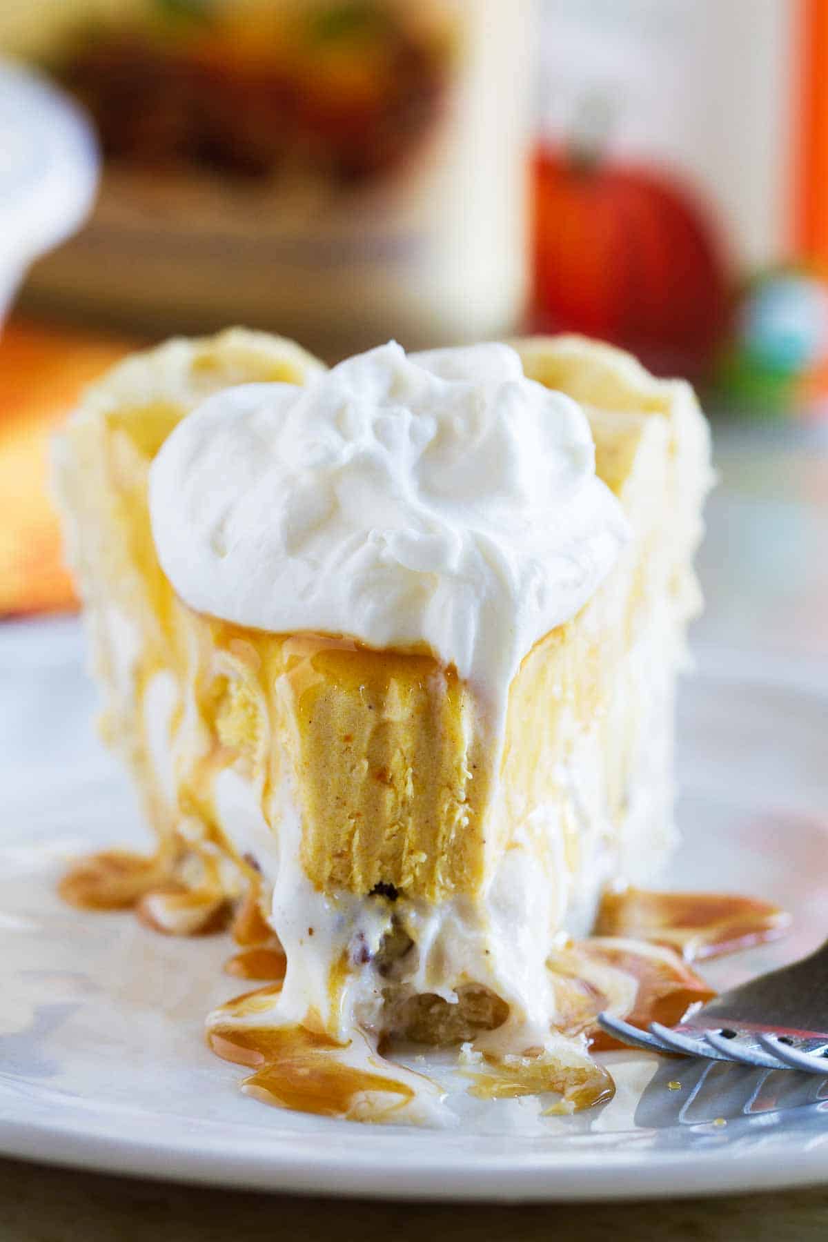 Slice of pumpkin and butter pecan ice cream pie with a bite taken from it.