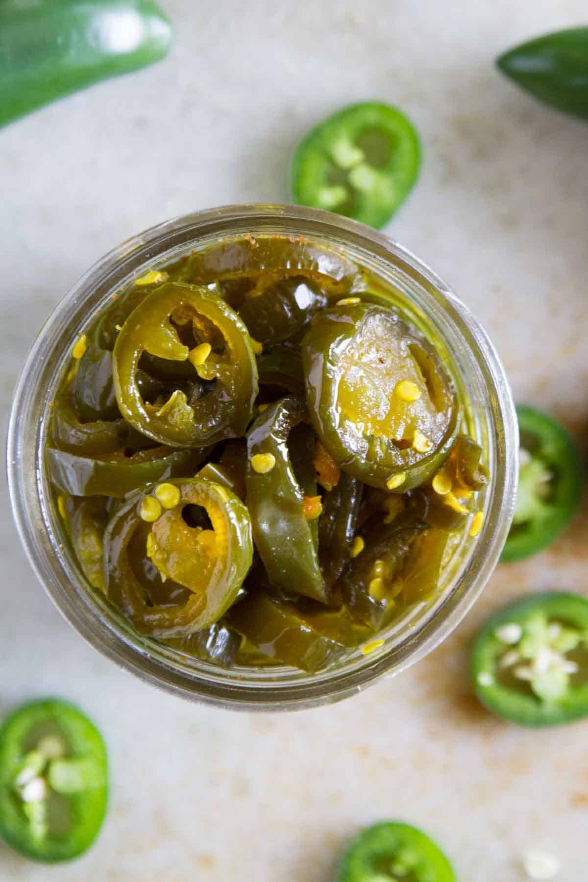 Top down view of a jar of candied jalapeños.