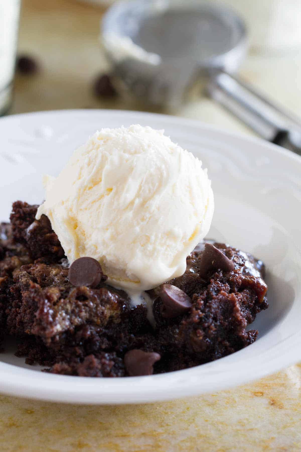 Bowl with chocolate caramel dump cake, topped with ice cream.