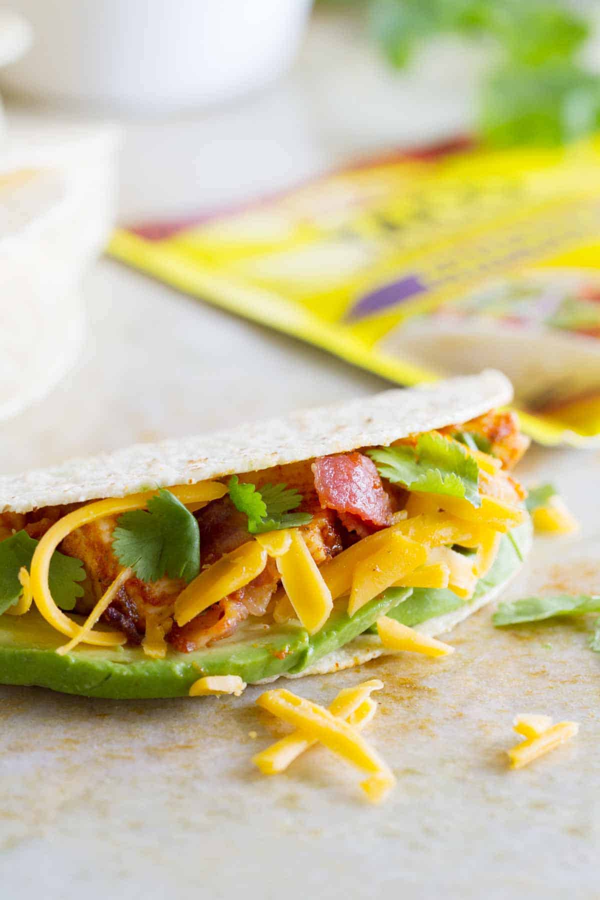 Chicken Bacon Avocado Taco with cheese coming out of it.