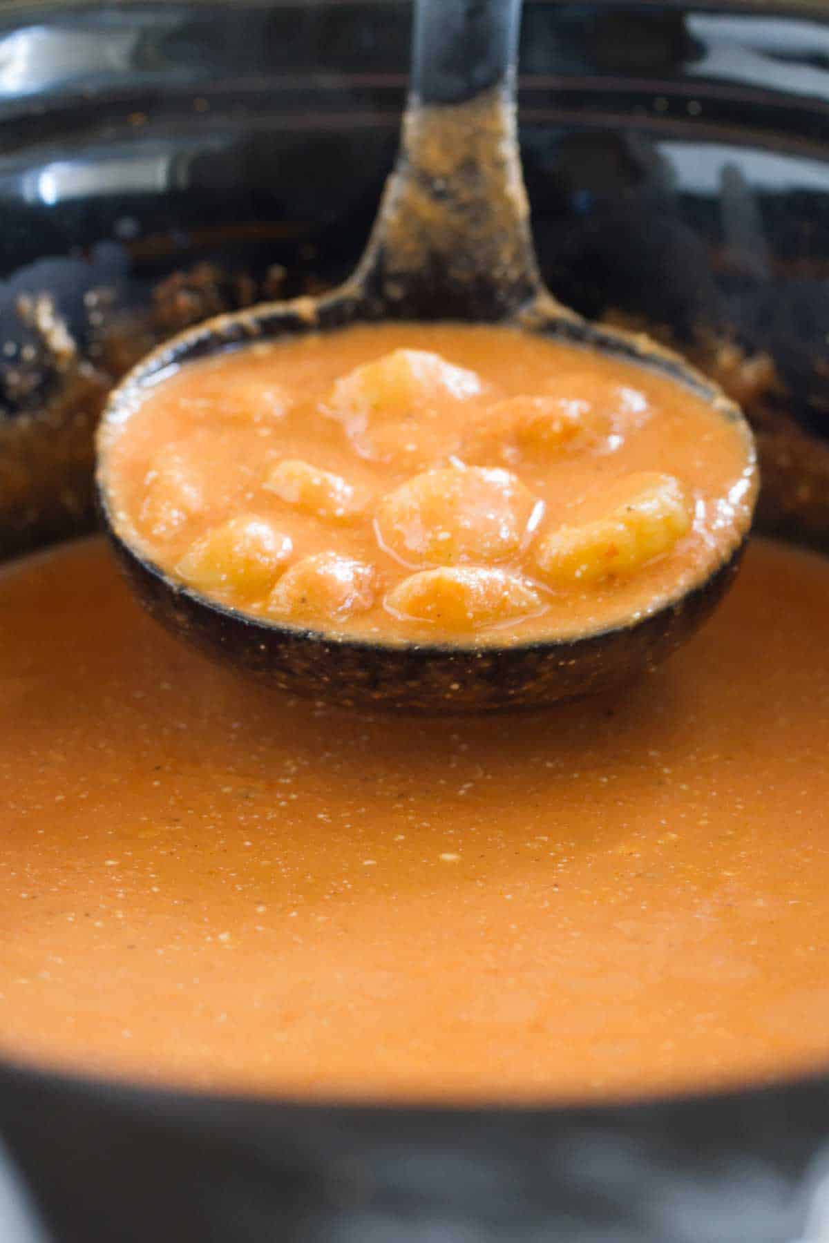 Ladle with Creamy Slow Cooker Tomato Soup with Gnocchi.