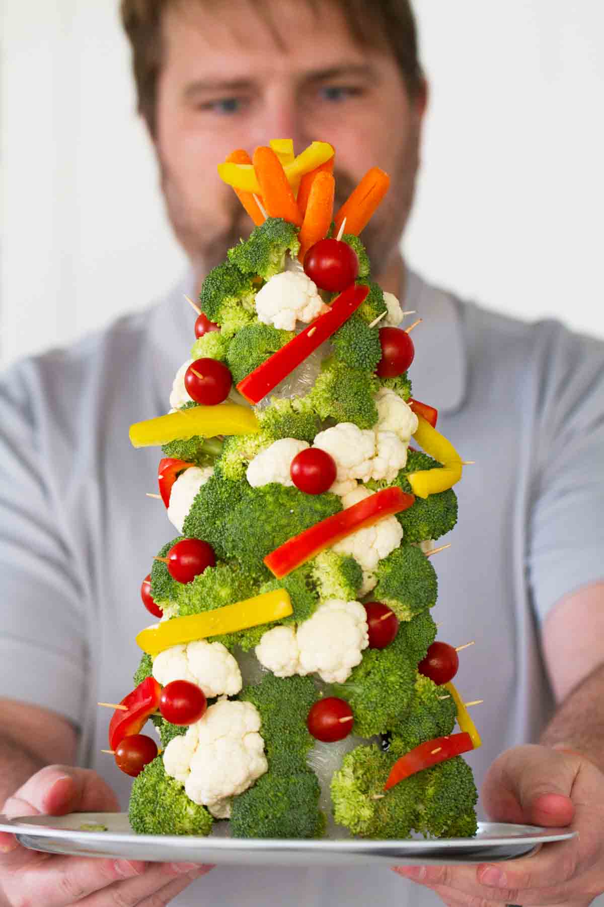 Man holding a Christmas tree made from vegetables.