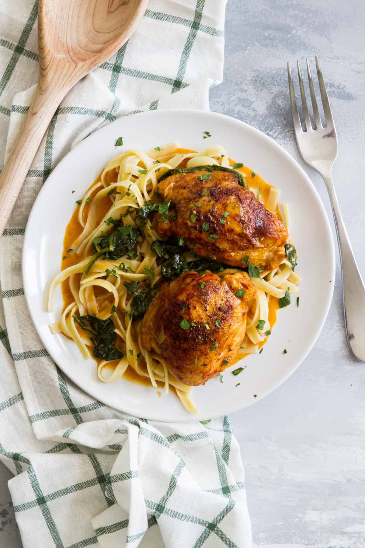 Serving of Garlic Paprika Chicken Thighs served over past on a plate.