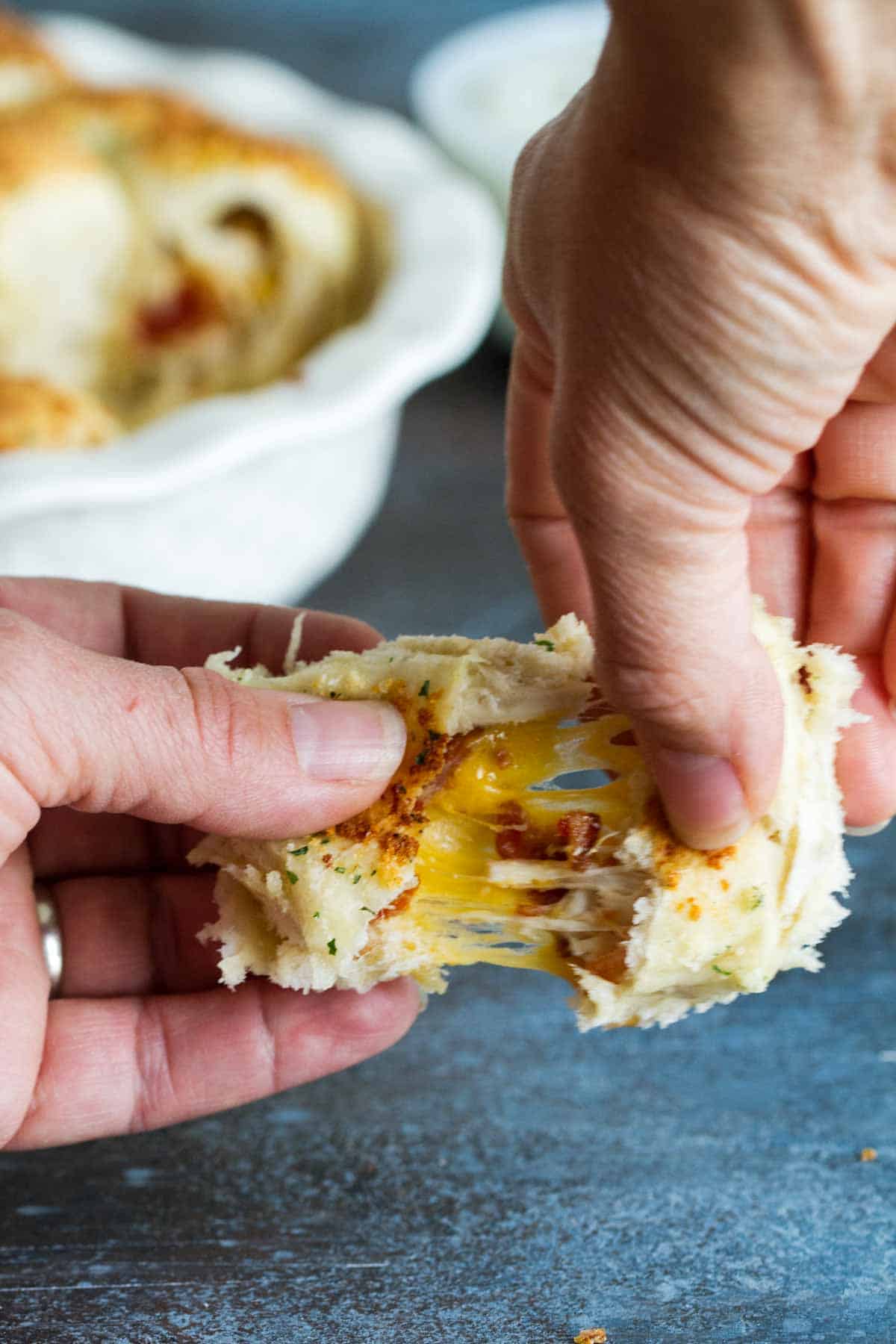 Pulling a stuffed pizza roll apart to show filling and cheese pull.