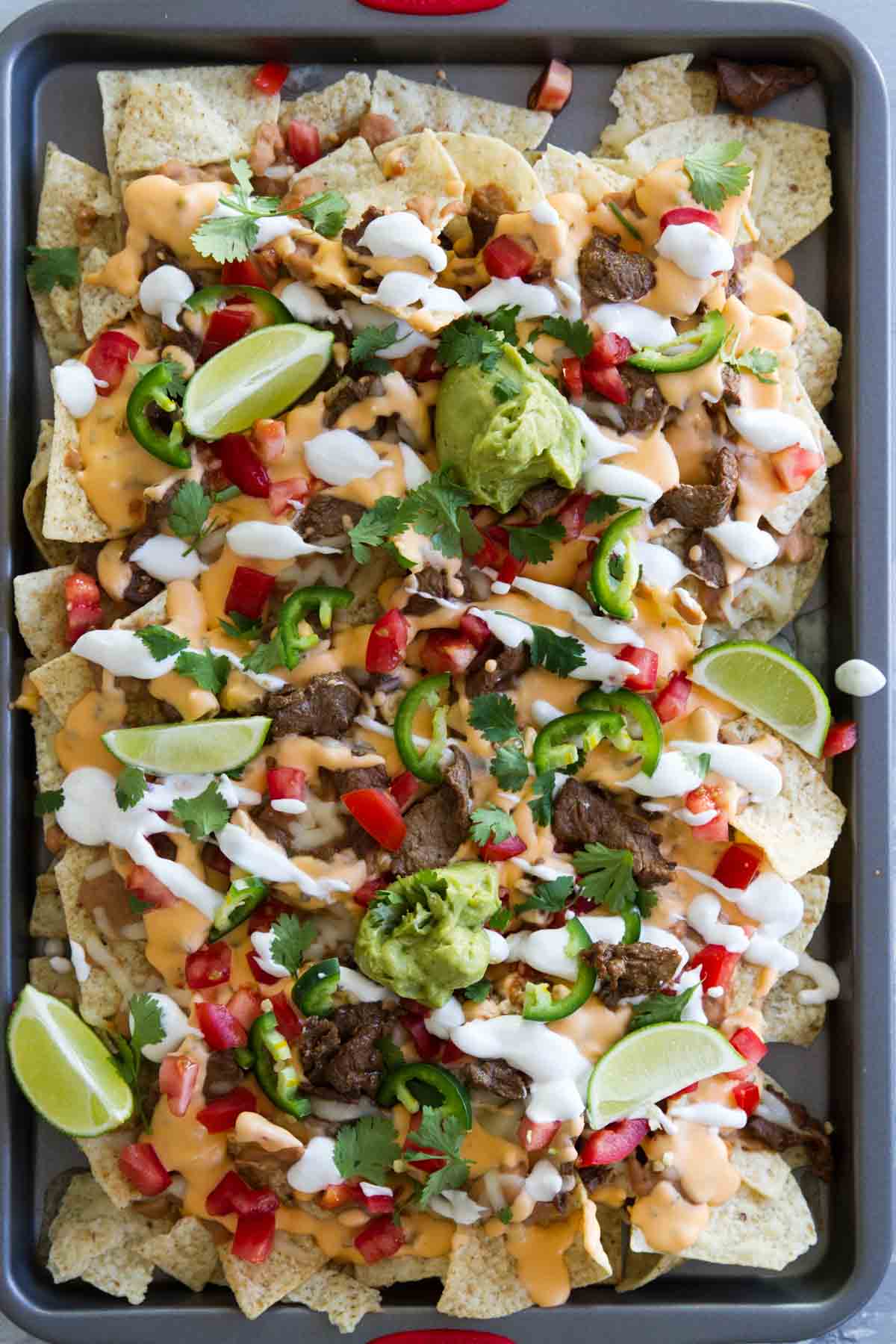 Sheet Pan Steak Nachos Supreme with lot of toppings.