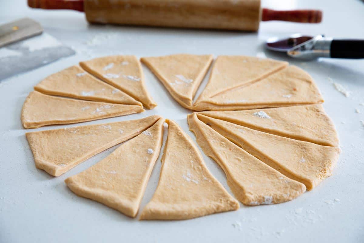 rolling out and cutting dough for homemade crescent rolls