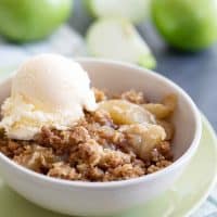 bowl of apple crisp topped with vanilla ice cream