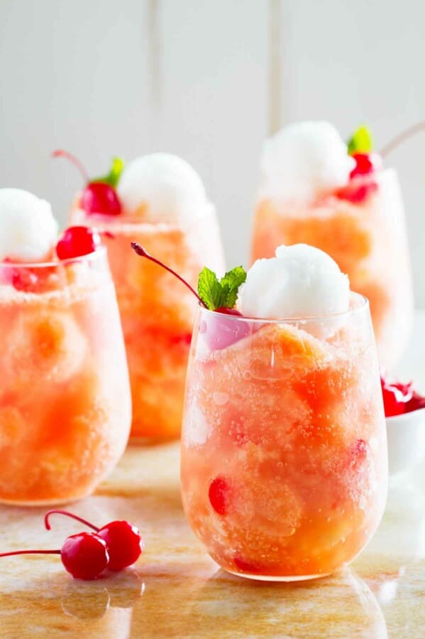 glasses of fruit freeze punch topped with sorbet and cherries