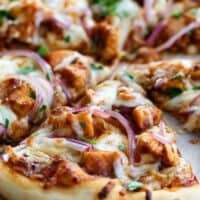 bbq chicken pizza topped with bbq sauce, chicken, onions and cilantro