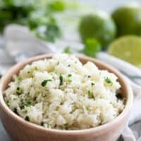 bowl of cilantro lime rice with limes in the background