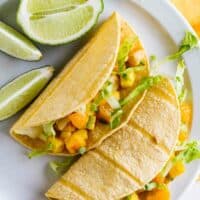 overhead view of citrus fish tacos with fruit salsa with limes on the plate