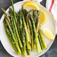 overhead view of roasted asparagus on a white plate