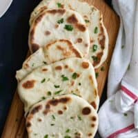 overhead view of naan bread on a cutting board with a white towel