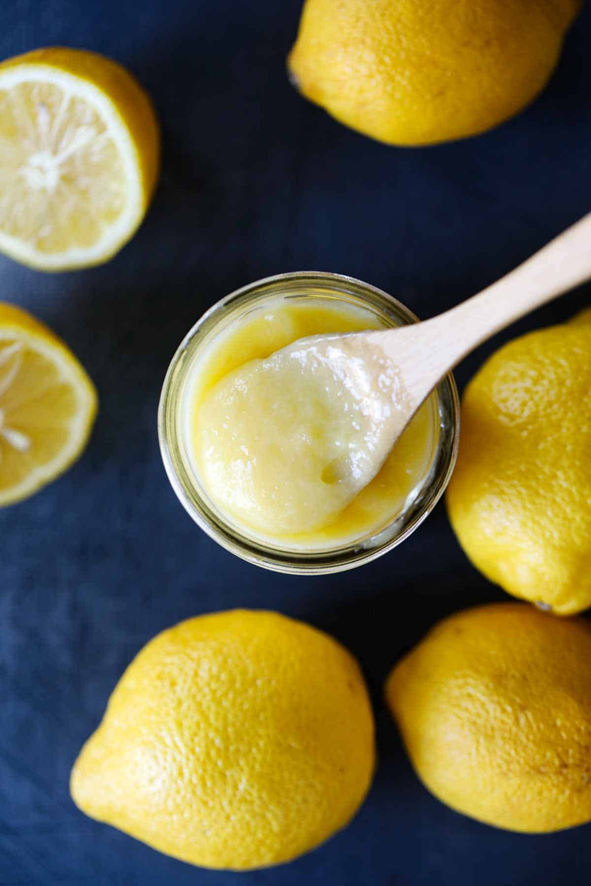 overhead view of jar of lemon curd with a wooden spoon in it
