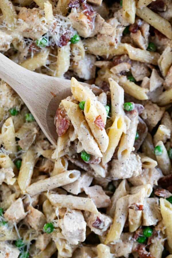 Overhead view of wooden serving spoon with Chicken Bacon Pasta.