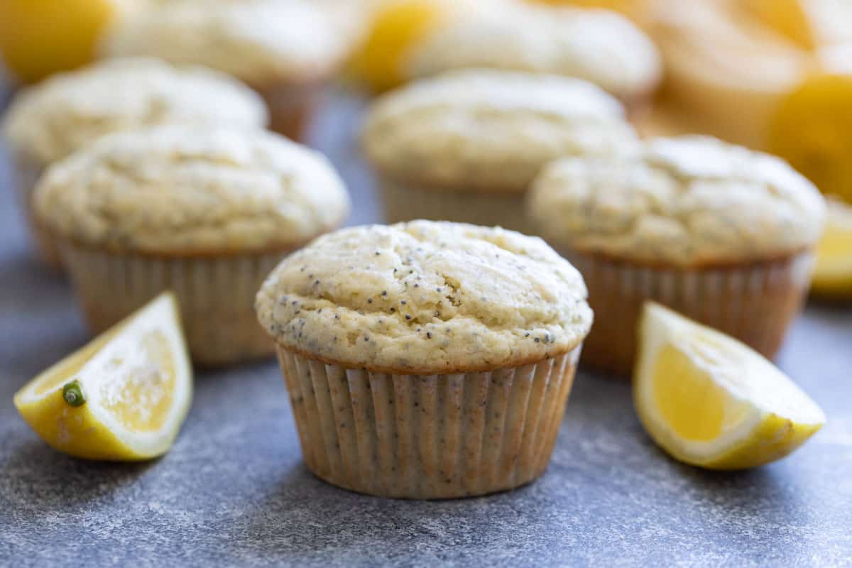 Lemon Poppy Seed Muffins in cupcake liners with sliced lemons on the side.