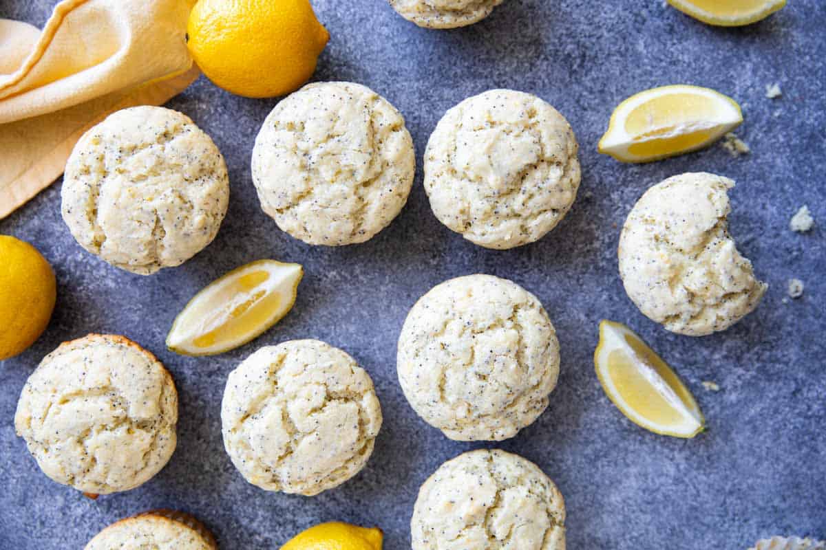 Lemon Poppy Seed Muffins with fresh lemons and a bite taken from one muffin.