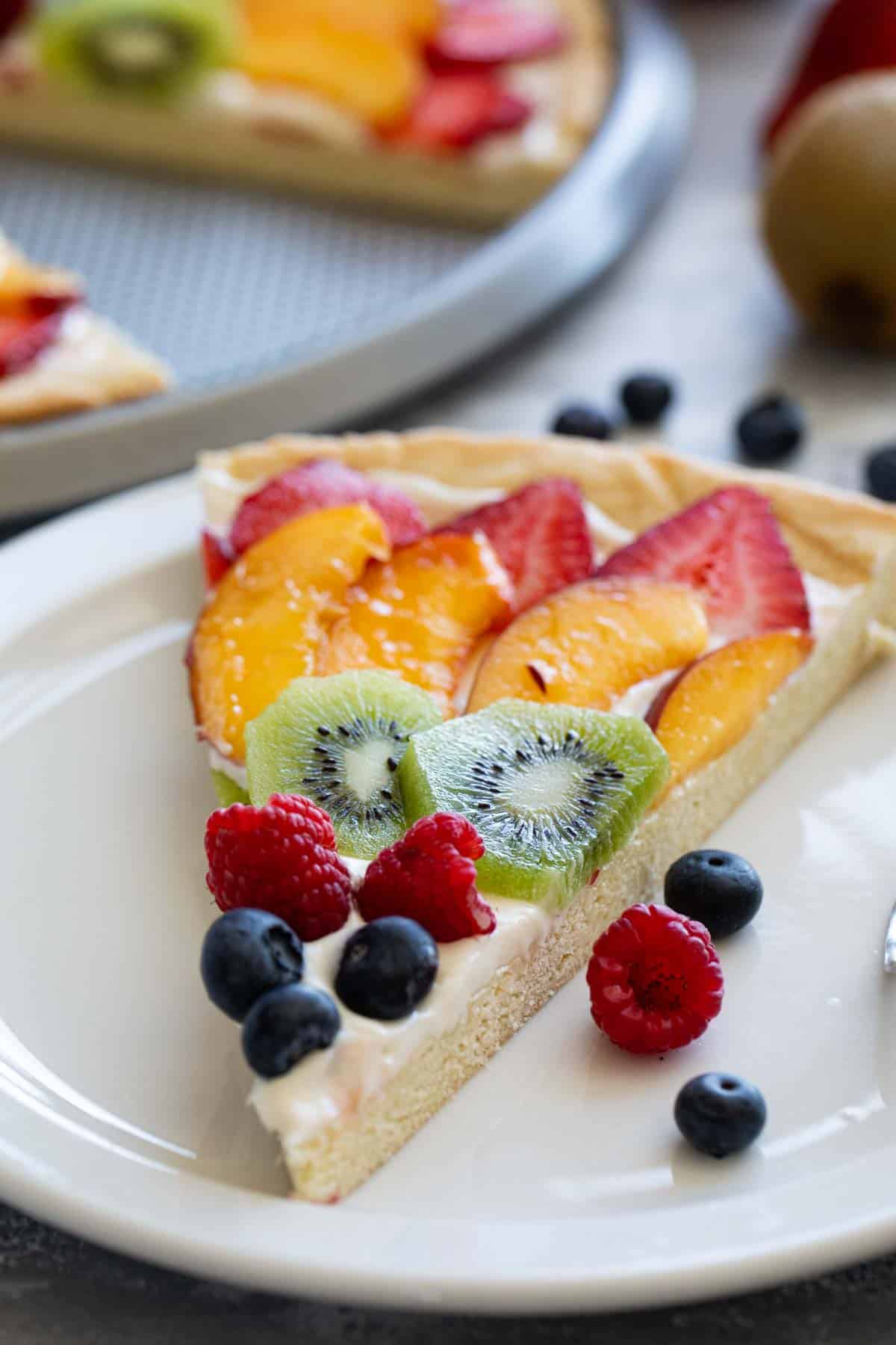 Slice of fruit pizza on a plate.