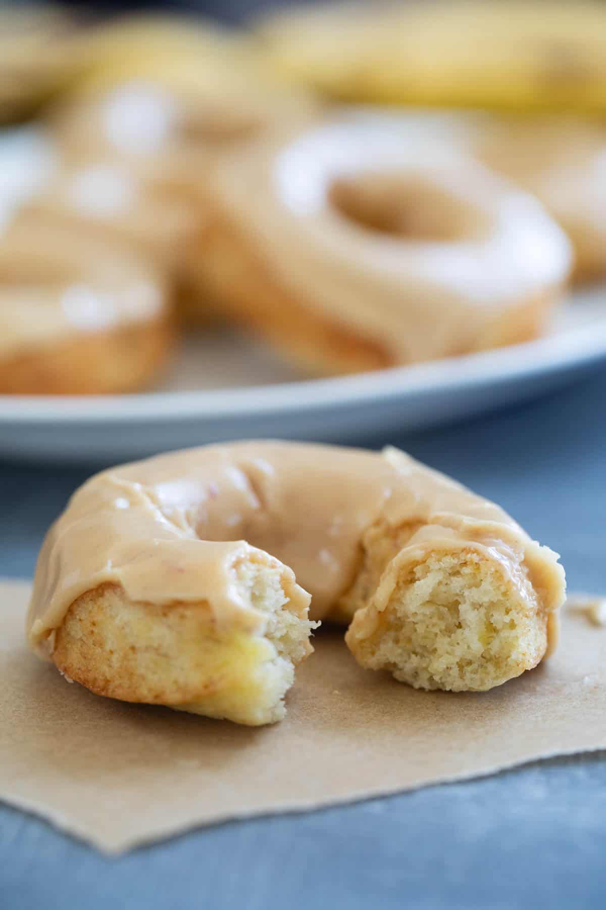 Baked banana donut with peanut butter icing with a bite taken from it.
