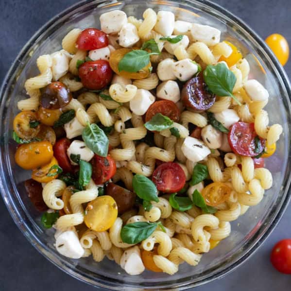 Bowl filled with Caprese Pasta Salad with pasta, tomatoes, mozzarella, and basil.