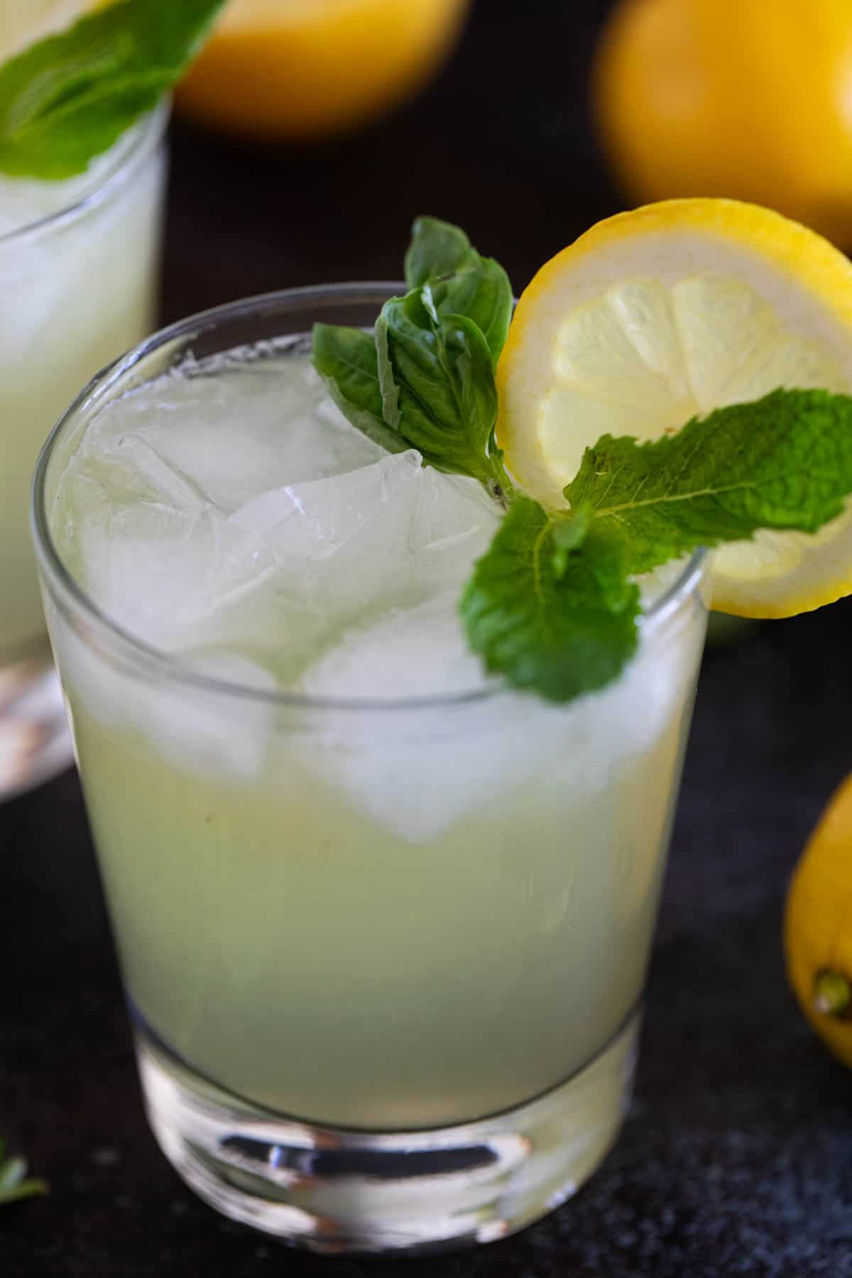 Mint and Basil Lemonade with ice and fresh lemon slice.
