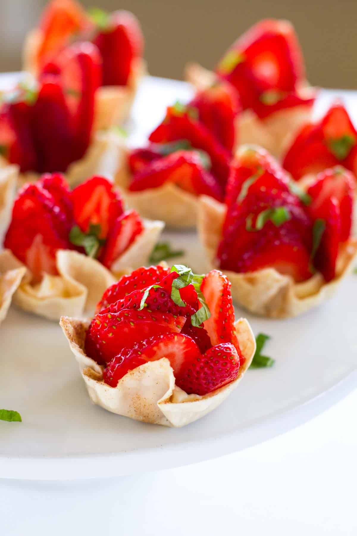 Strawberry Wonton Cups filled with cream cheese and topped with sliced strawberries.