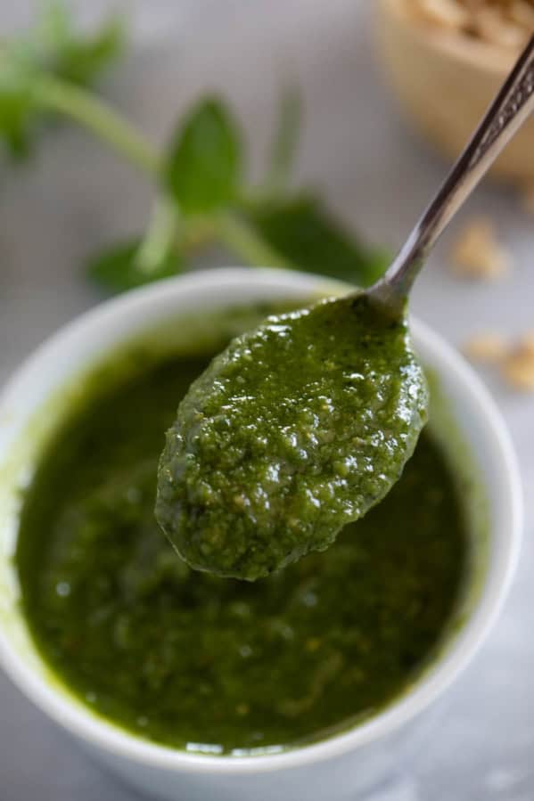 Spoonful of fresh basil pesto over a bowl.