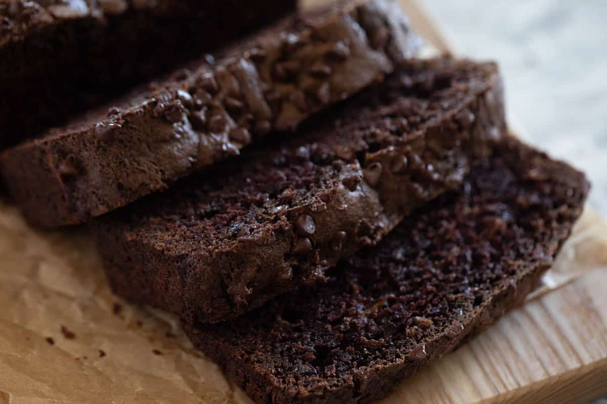 A sliced loaf of chocolate zucchini bread on a cutting board.