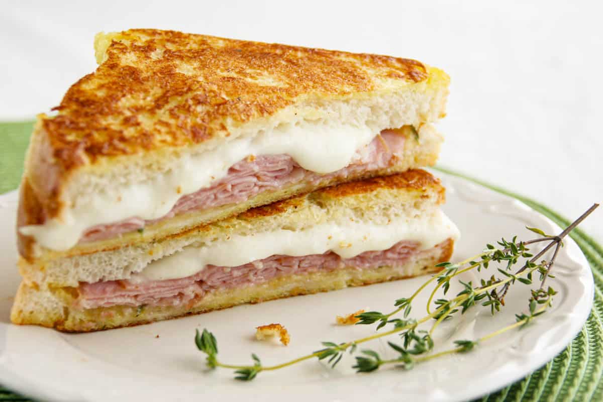Italian Style Monte Cristo cut in half and stacked with fresh thyme on a plate.