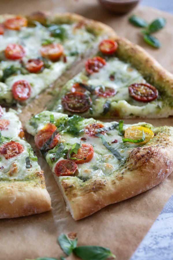 Pesto Pizza with tomatoes and fresh basil cut into slices.