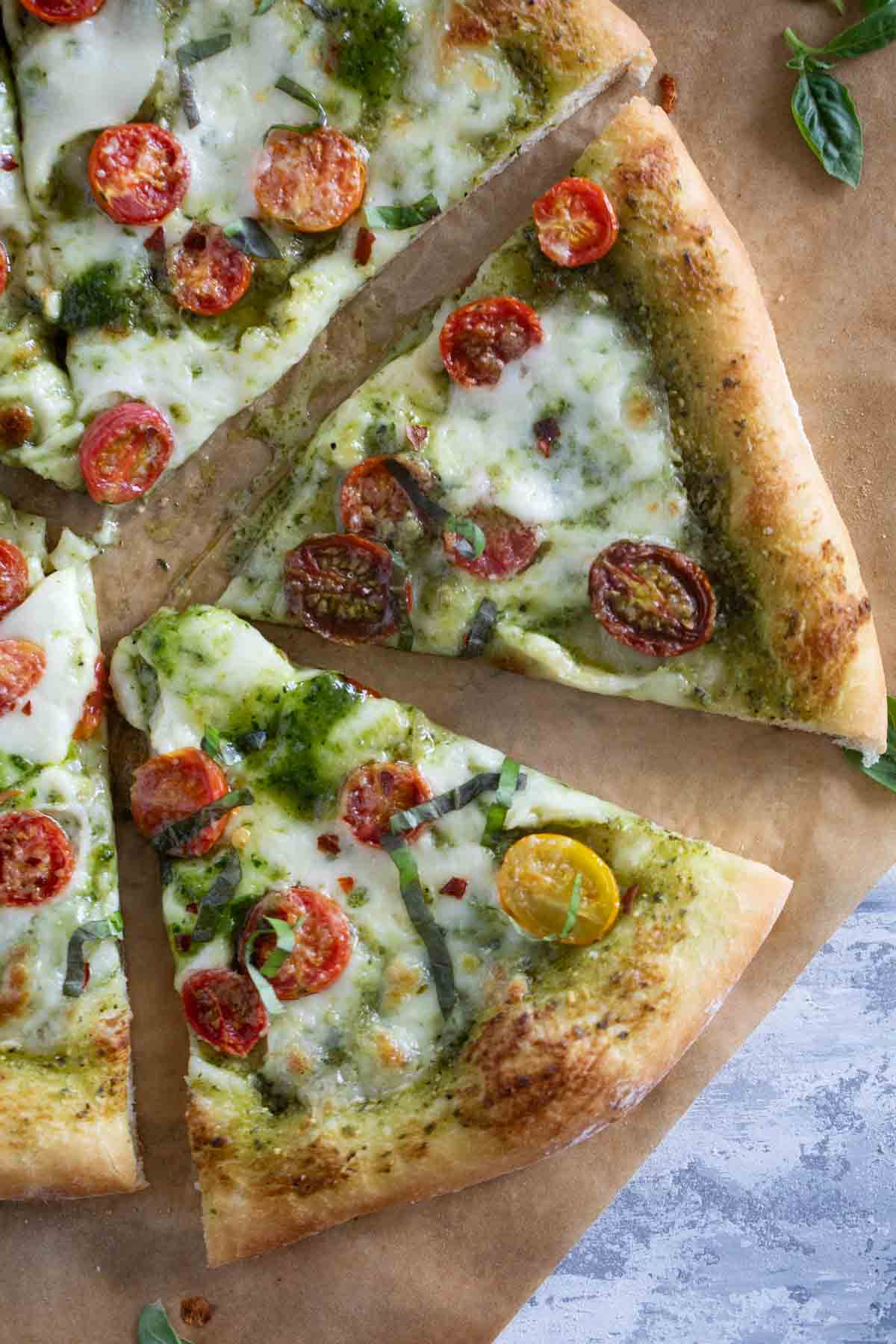 Sliced pieces of Pesto Pizza topped with tomatoes.