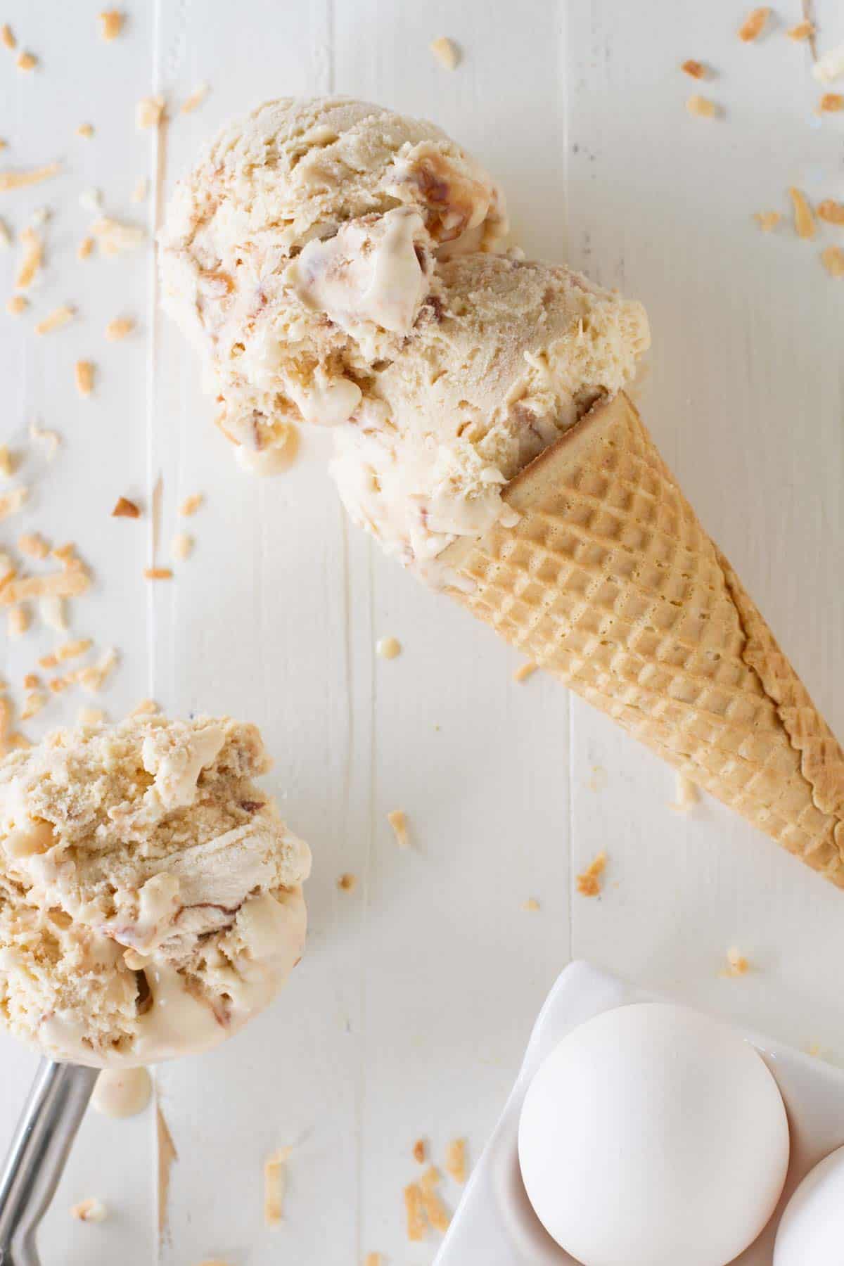 Two scoops of salted caramel ice cream with fudge and toasted coconut on a sugar cone.
