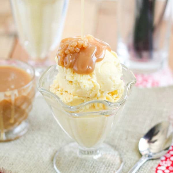 Pouring homemade salted caramel sauce over the top of sweet corn ice cream in a glass cup.