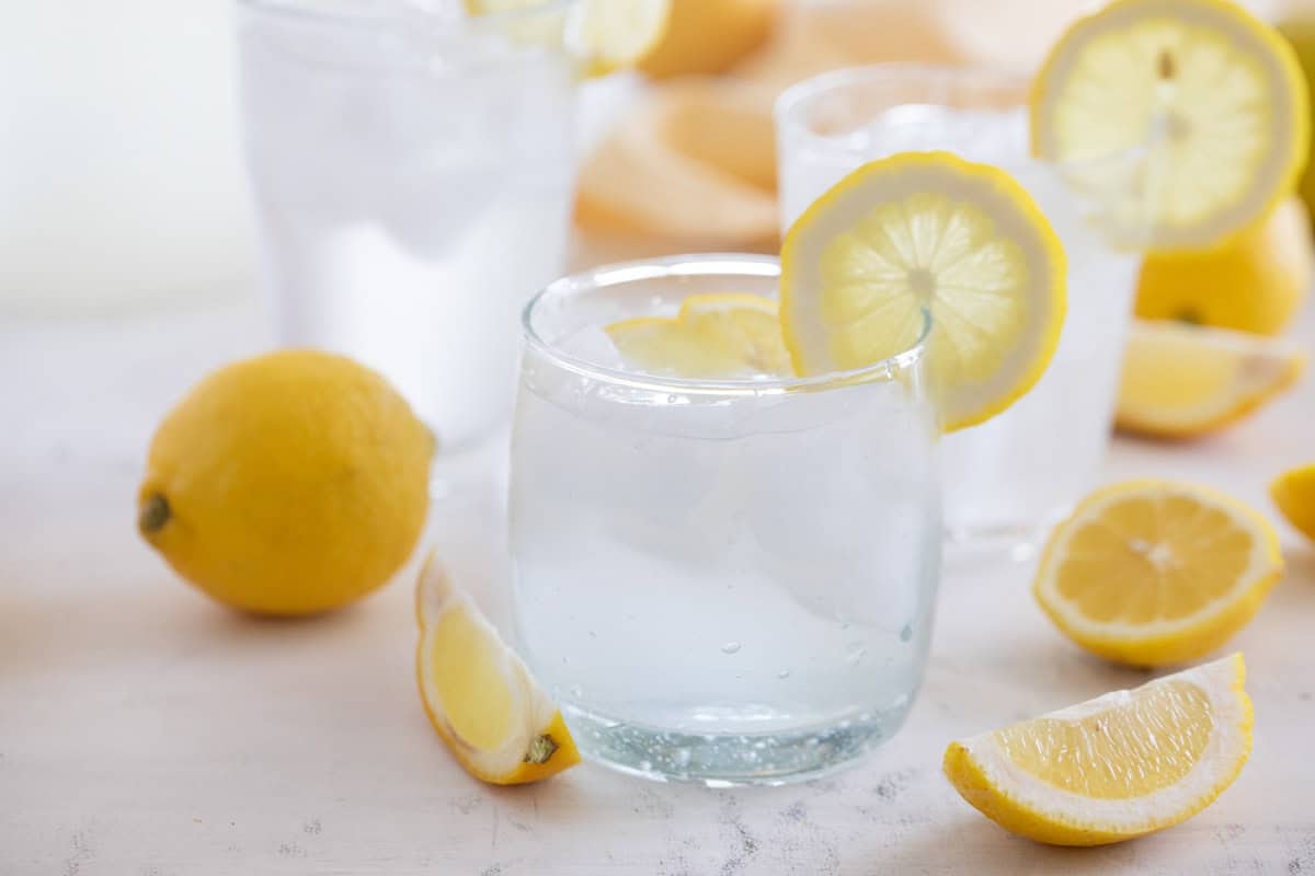 Glass filled with sweet lemon water with a lemon slice on the cup.