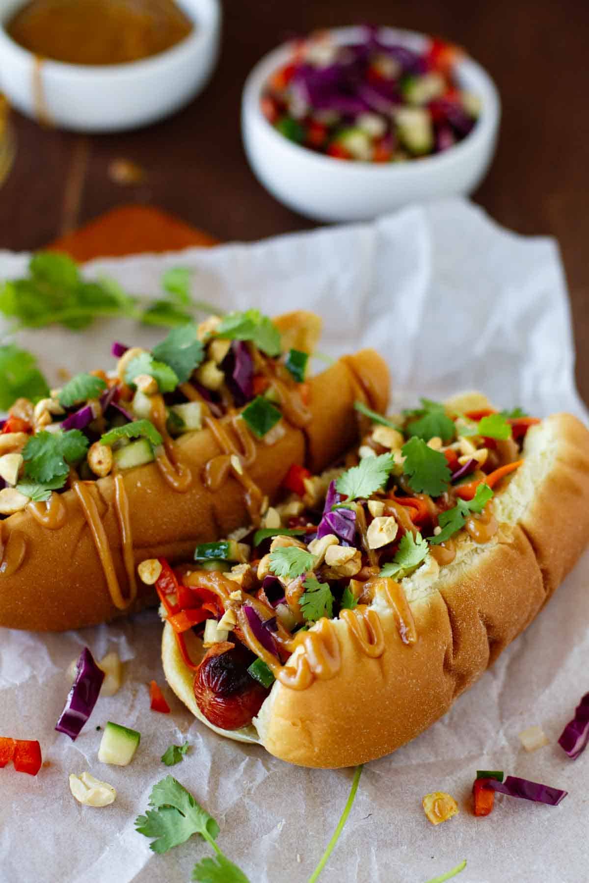 Two Thai Style Hot Dogs topped with peanut sauce.