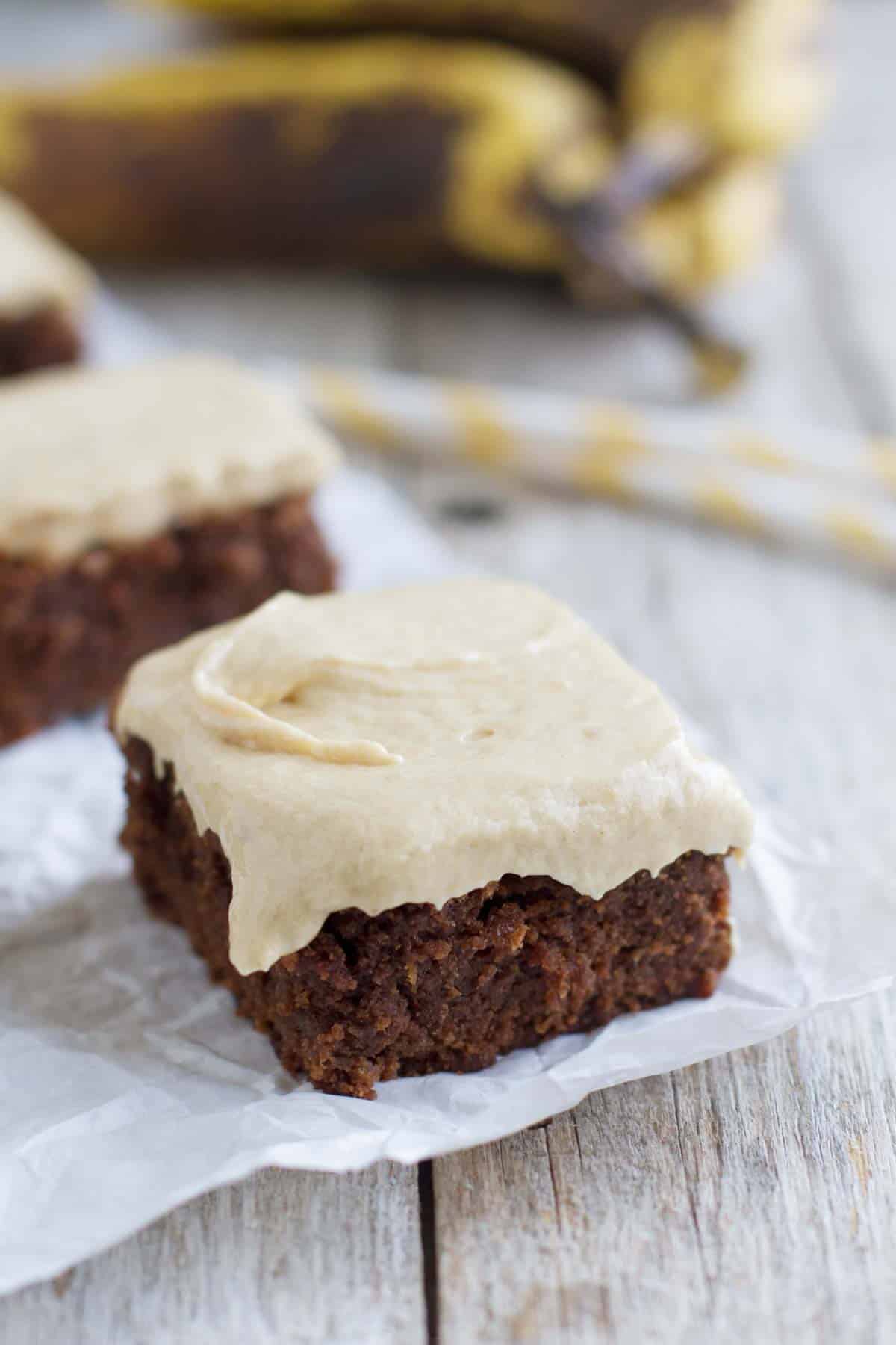 Banana Brownie topped with peanut butter banana frosting on parchment.