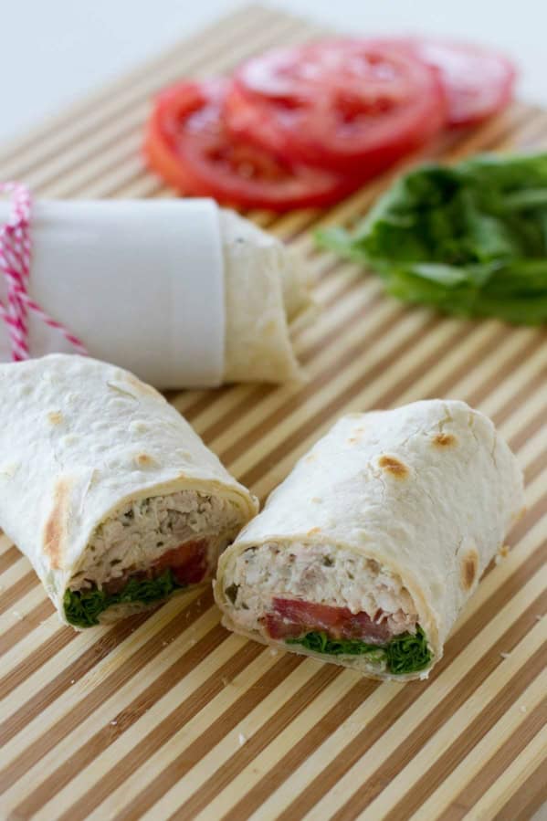 Chicken pesto wrap with tomato and lettuce, cut in half.