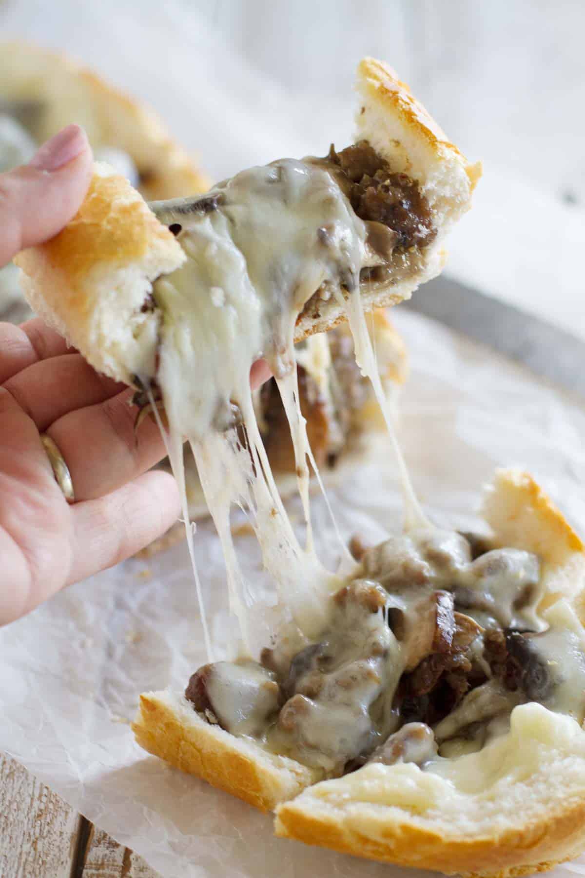 Cheese pull on a piece of French Bread Pizza with Sausage and Portobello Mushrooms.