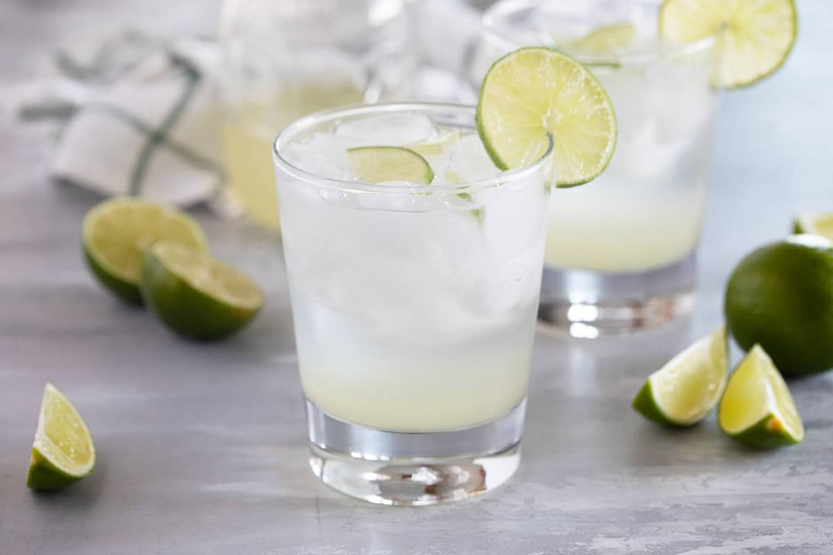 Glass of sparkling ginger limeade in a glass with ice and lime slices.