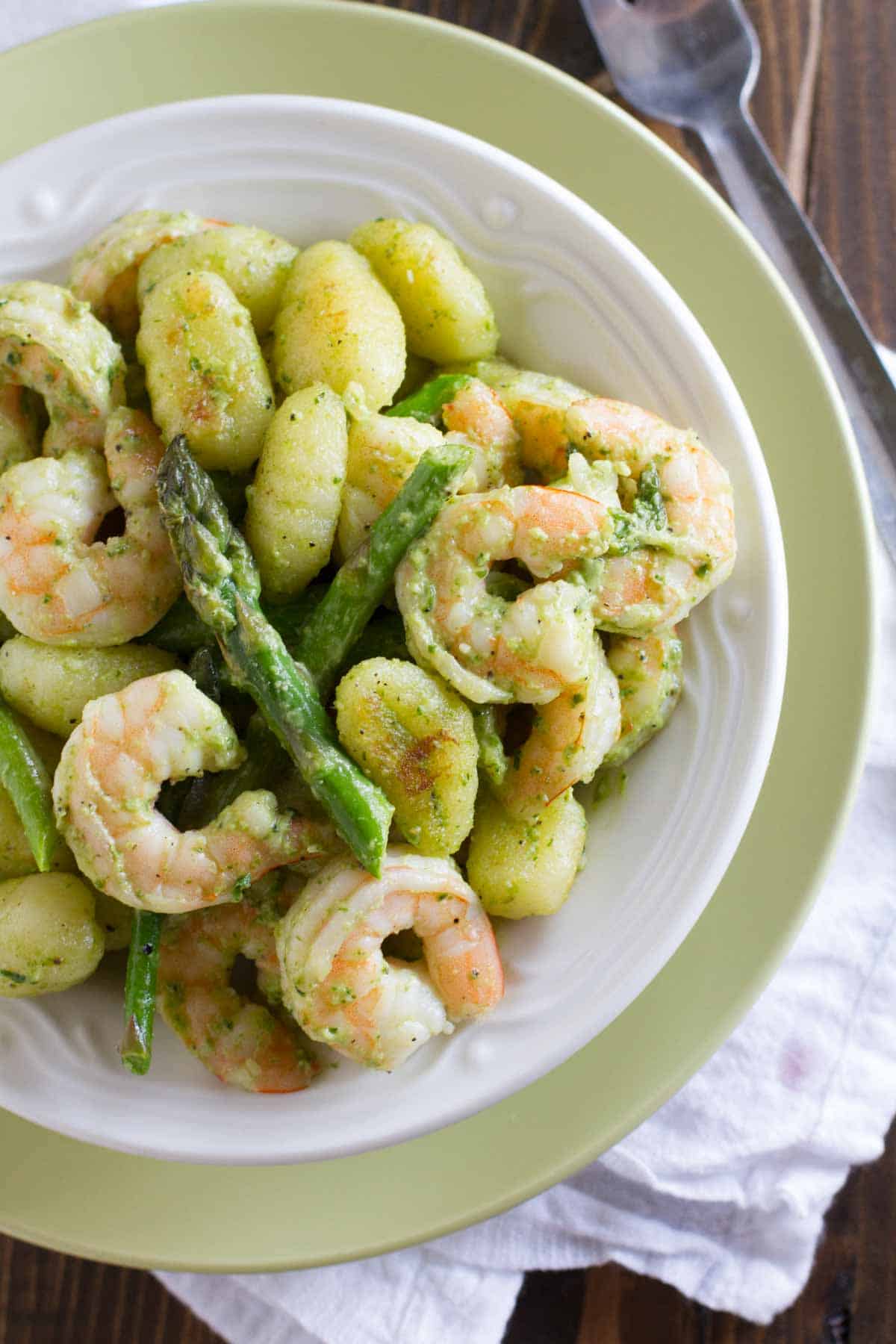 Bowl filled with gnocchi with pesto, shrimp, and asparagus.