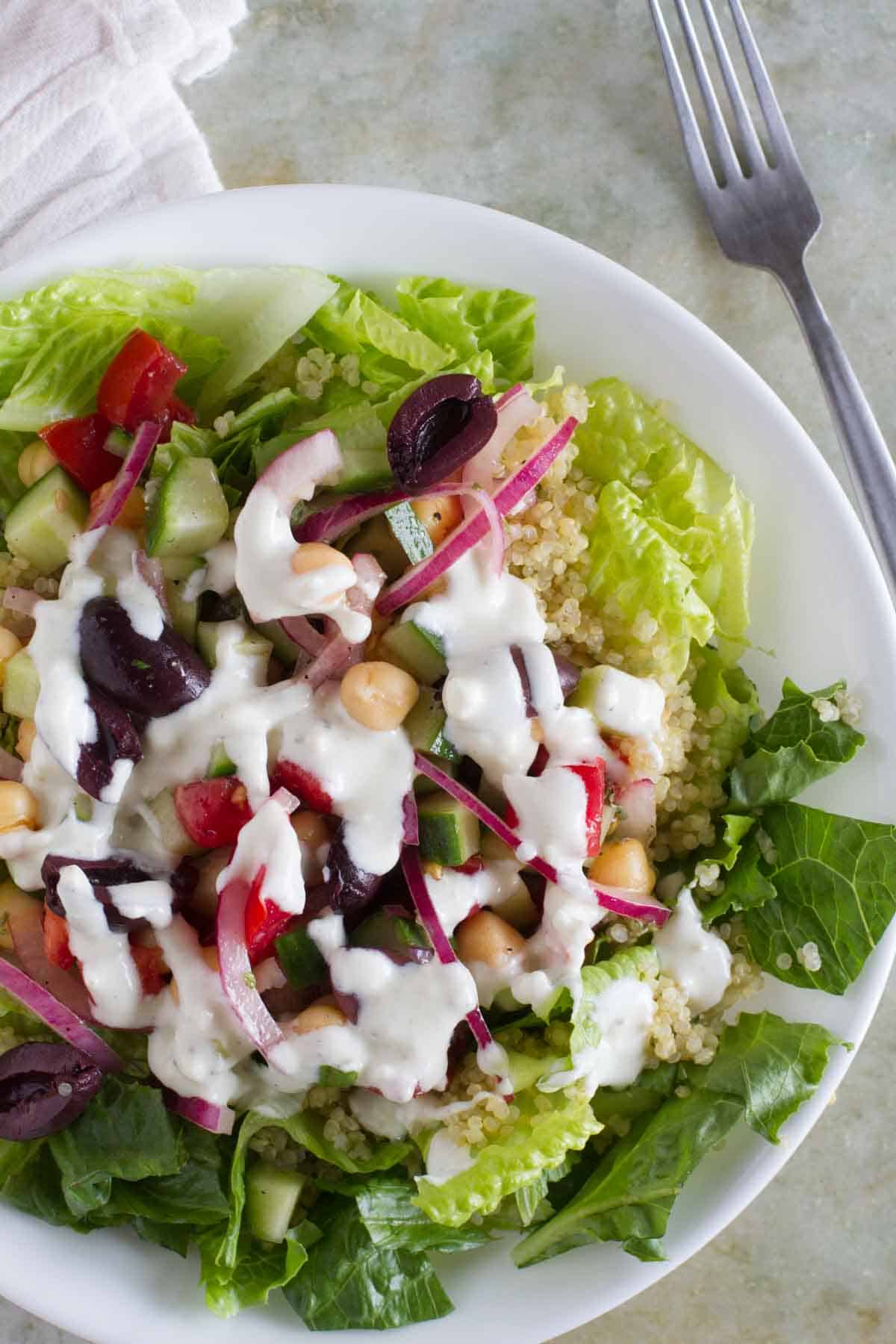 Overhead view of Greek Quinoa Salad topped with red onions, olives, tomatoes, and chickpeas.