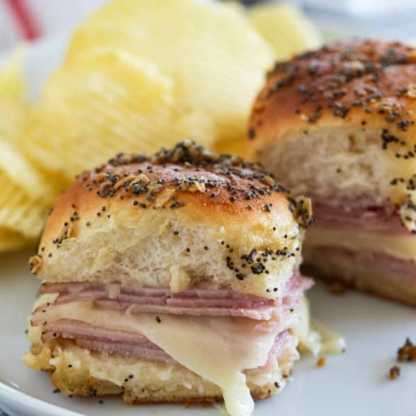 Two ham and cheese sliders on a plate with potato chips.