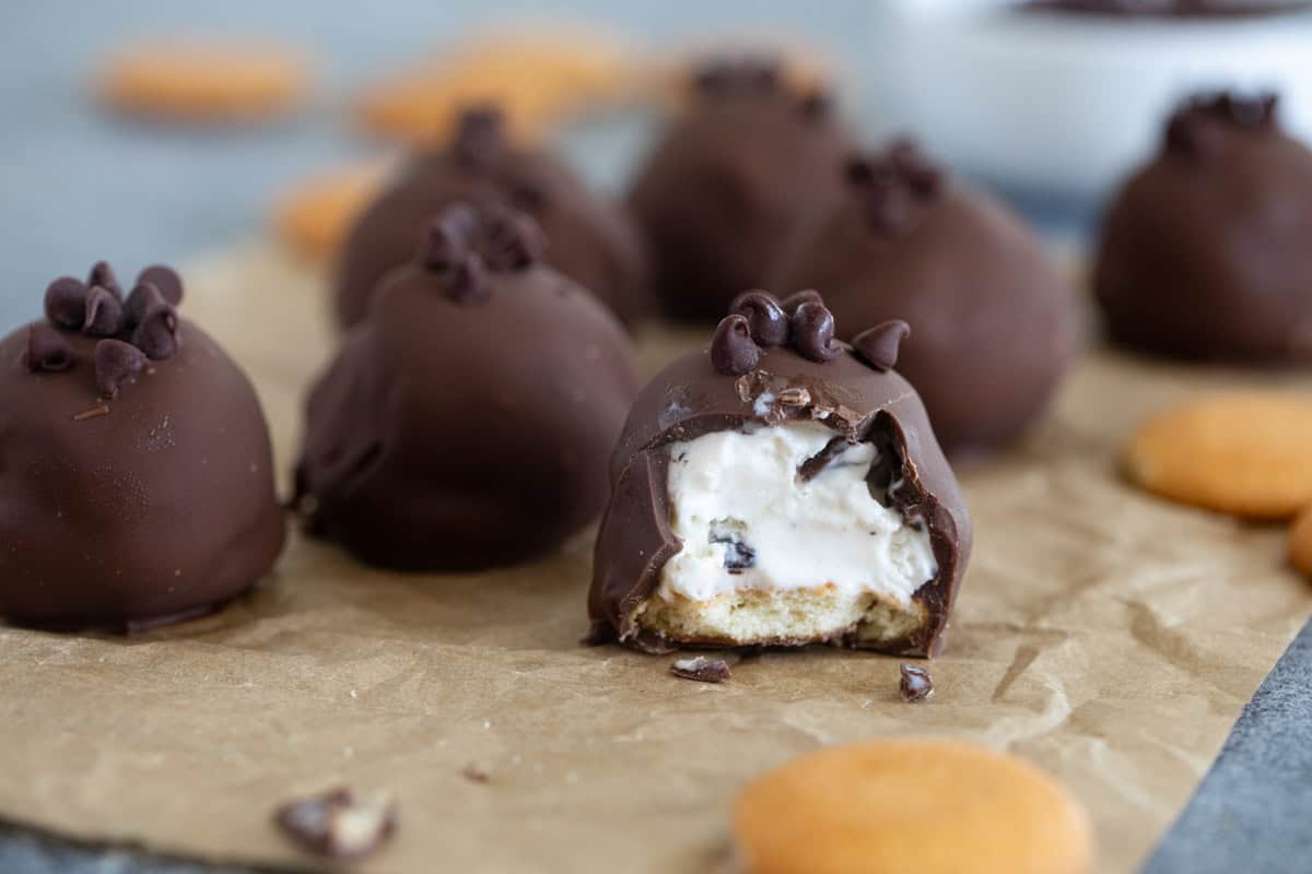 Ice cream bonbons covered in chocolate, with a bite taken from one.